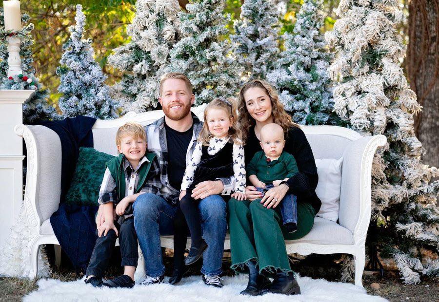 My wife, our three kids and me on a white settee among snowy Christmas trees